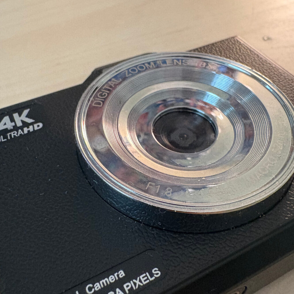 A close up picture of a digital camera, with the lens as the main focus point.