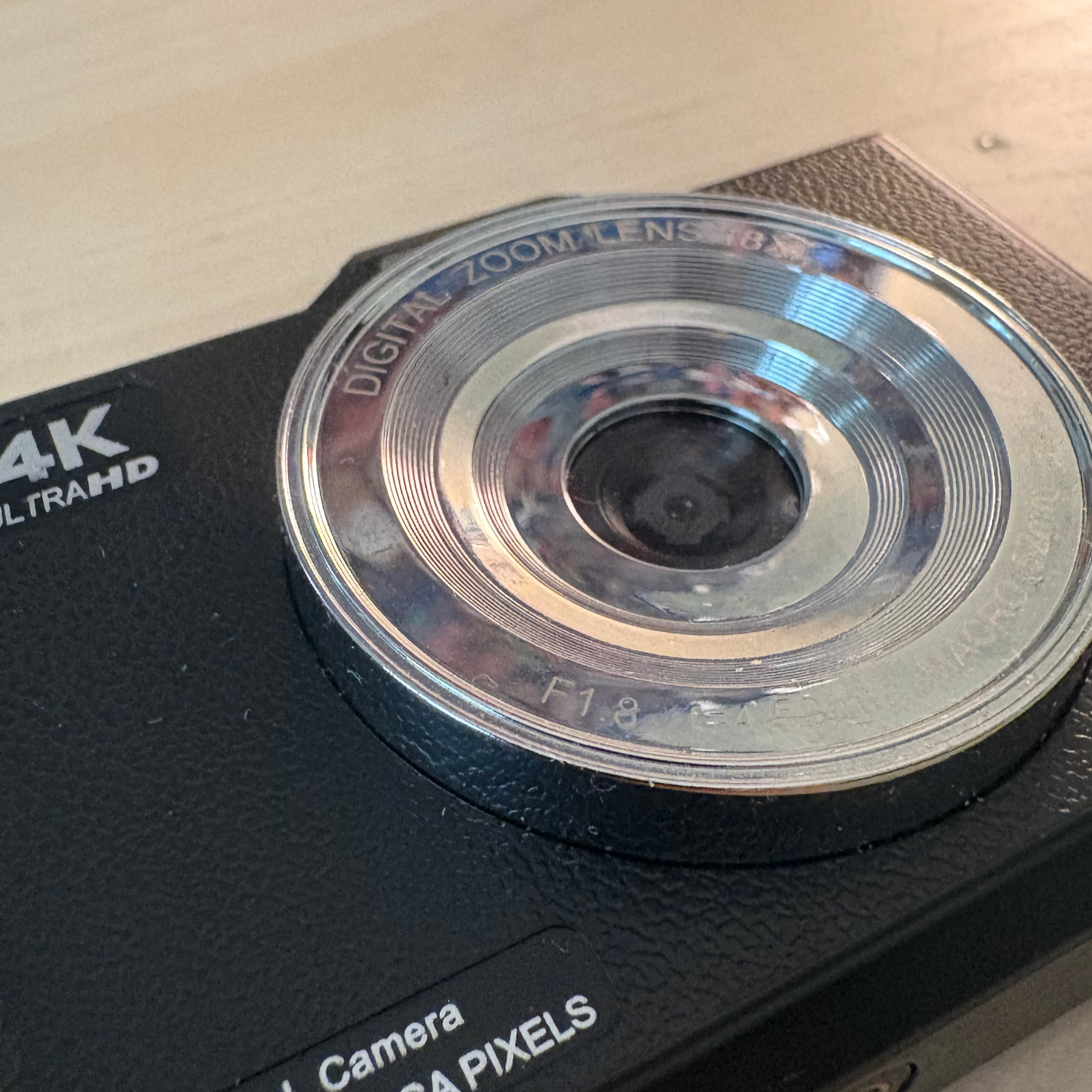 A close up picture of a digital camera, with the lens as the main focus point.