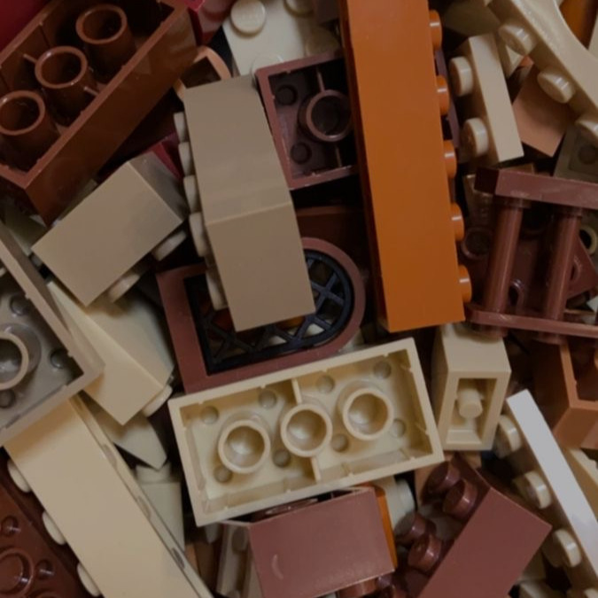 A close up picture of lego pieces, arranged messily together. The pieces vary in shape and size, and are all of neutral colour including brown, beige and cream