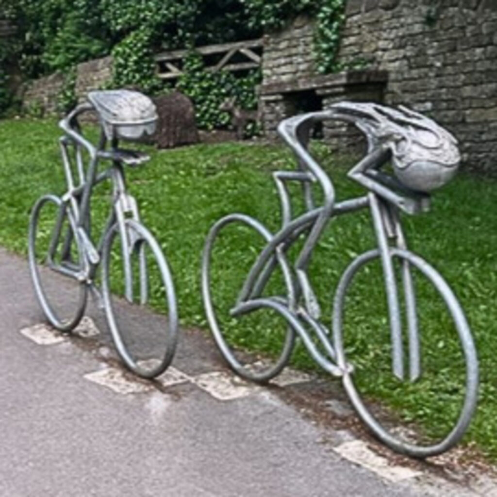 A picture of a statue of two stick figures on road, racing bikes