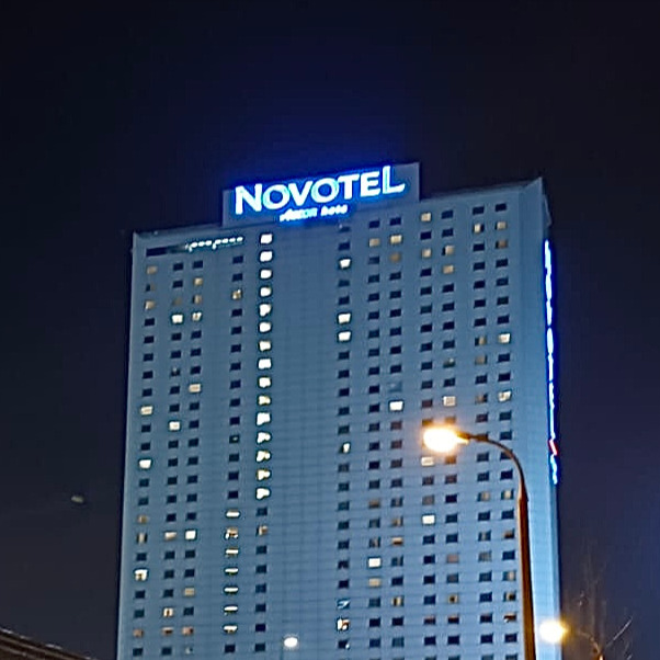 A picture of a tall building that is Novotel hotel from a distance and looking up.